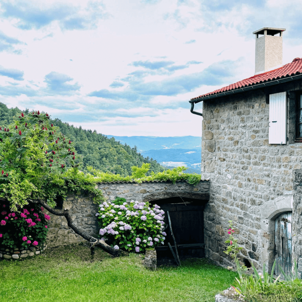 gîte ardèche 8 personnes - gite la comballe des gites de costerousse en ardeche, jardin fleuri et ciel bleu nuageux