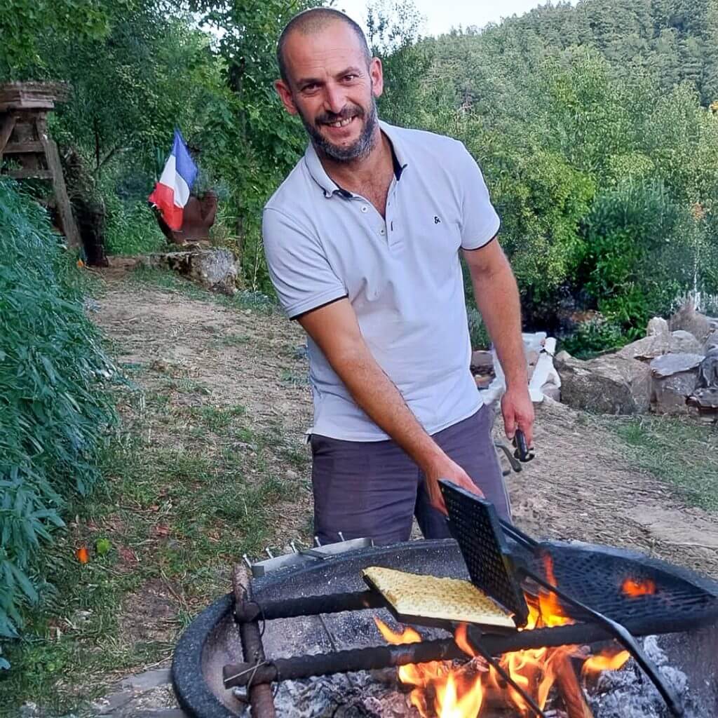 Gite Ardèche authentique - Arnaud en train de faire un barbecue à charbon pour les gites de costerousse en ardeche