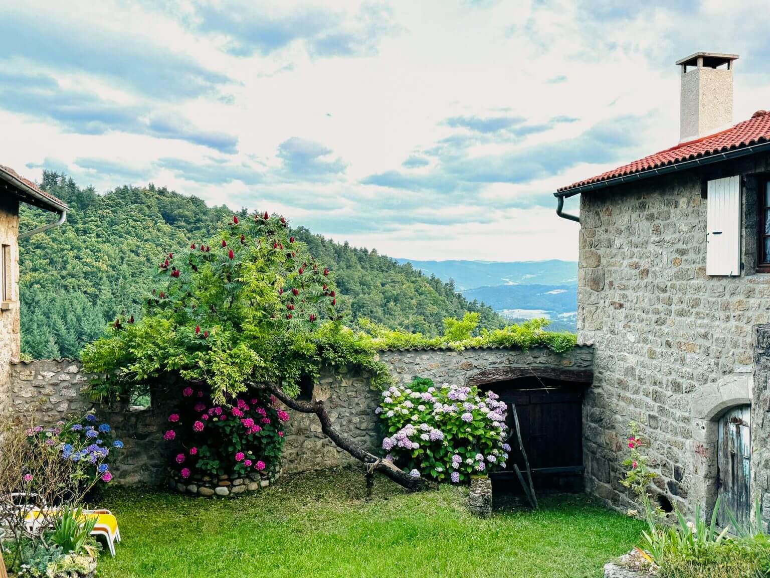 gite la comballe des gites de costerousse en ardeche, jardin fleuri et ciel nuageux en ardeche