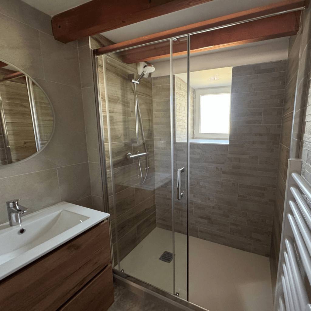 salle de bain moderne et lumineuse avec une grande douche a l'italienne, une fenêtre et une vasque lavabo